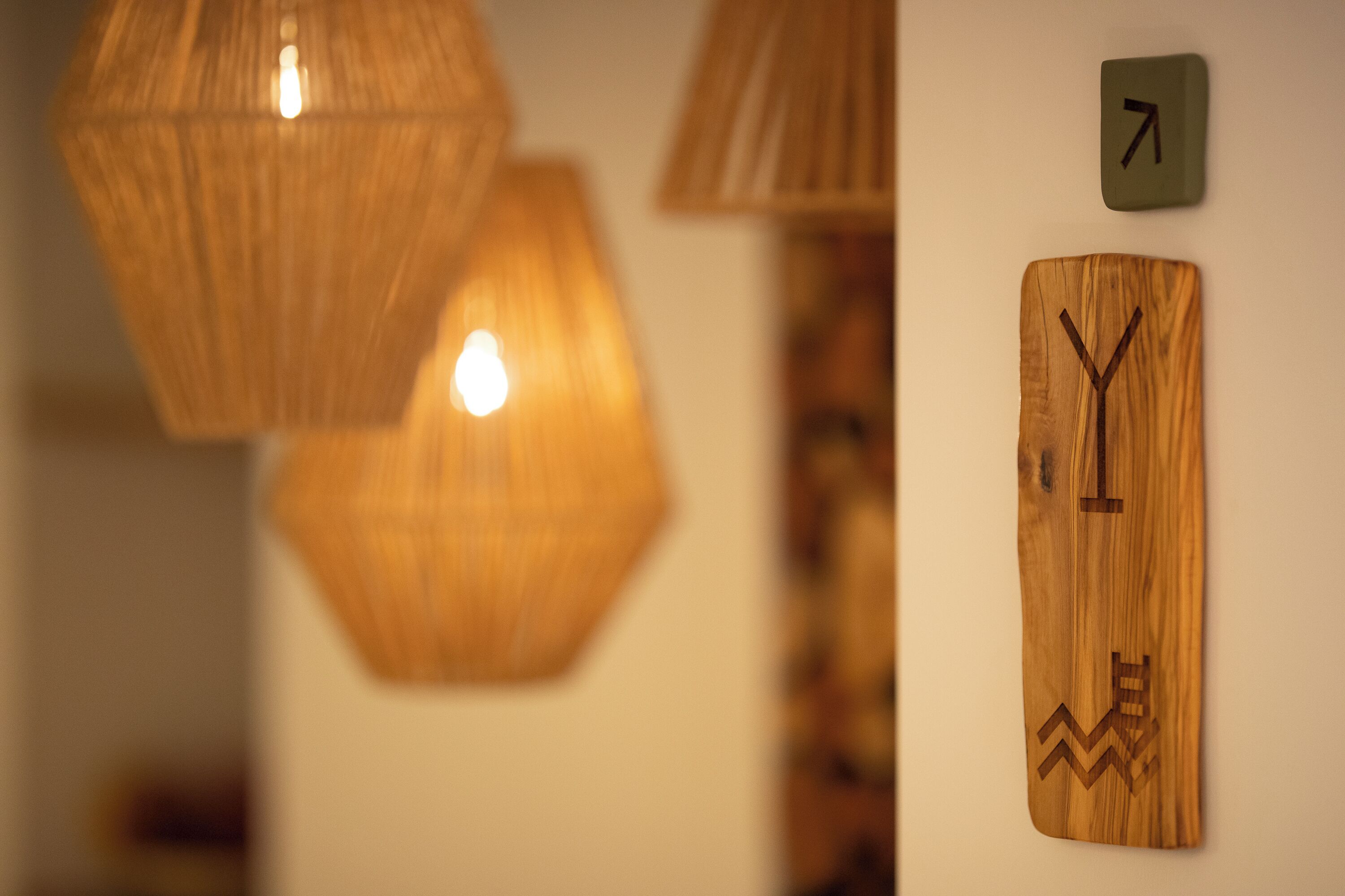 Decoración de madera en la pared con un diseño geométrico, un letrero señalizador y una lámpara colgante.