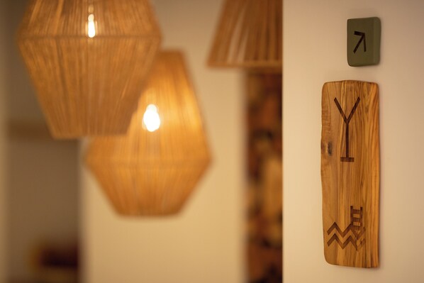 Decoración de madera en la pared con un diseño geométrico, un letrero señalizador y una lámpara colgante.