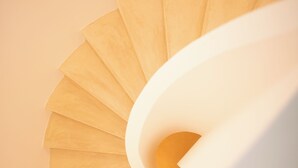 A spiral staircase with a light-colored wall and a white handrail. - Casa do Gadanha (Estremoz)