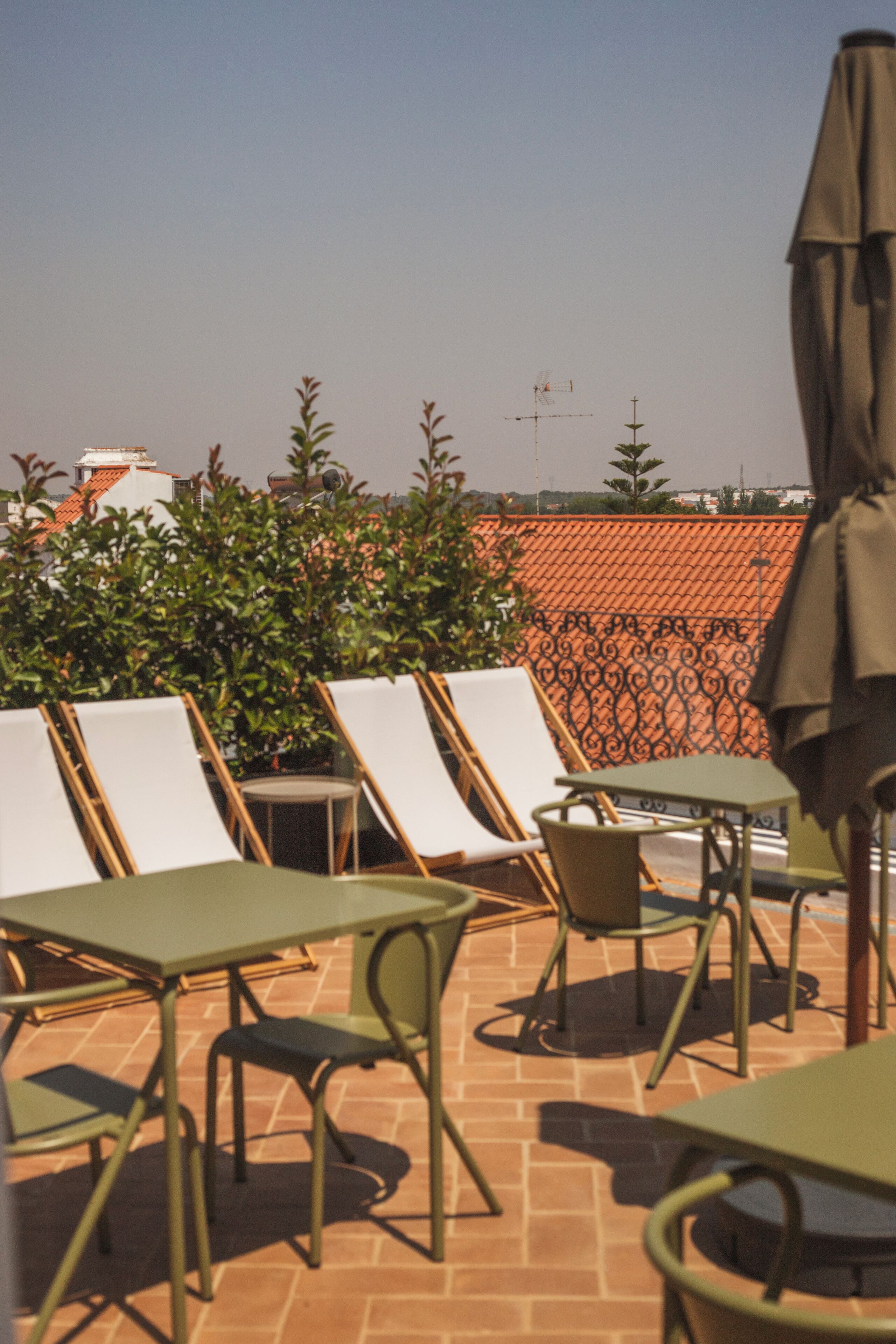Eine Dachterrasse mit Lounge-Möbeln und Tischen, mit Blick auf die Stadt und einem Zierzaun.
