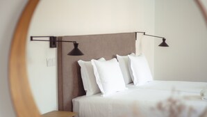 A neatly arranged bedroom with a bed, bedside tables, and a mirror reflecting the room. - Casa do Gadanha (Estremoz)