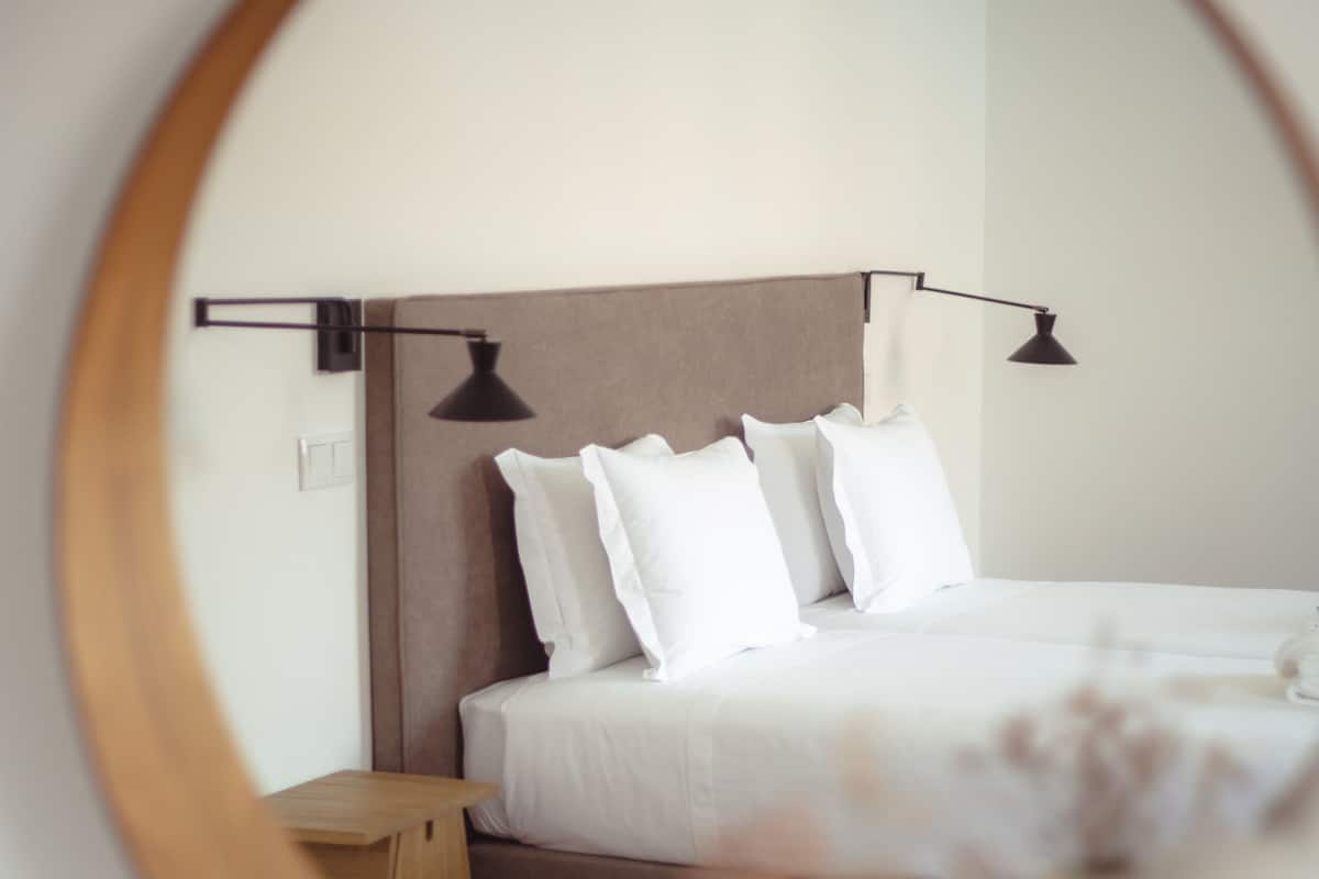 Une chambre à coucher bien rangée, avec un lit, des tables de chevet et un miroir qui reflète la pièce.