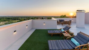 A rooftop terrace with sun loungers, a table, and a view of the sunset over a landscape. - Villa Kate Zadarvillas (Nin)