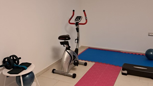 A small room with a stationary bike, a blue mat, a pink exercise mat, and a blue exercise ball. - Villa Kate Zadarvillas (Nin)