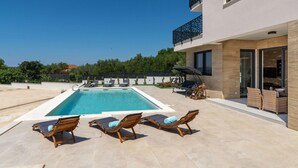 A modern pool area with a rectangular pool, lounge chairs, and a covered seating area. - Villa Kate Zadarvillas (Nin)