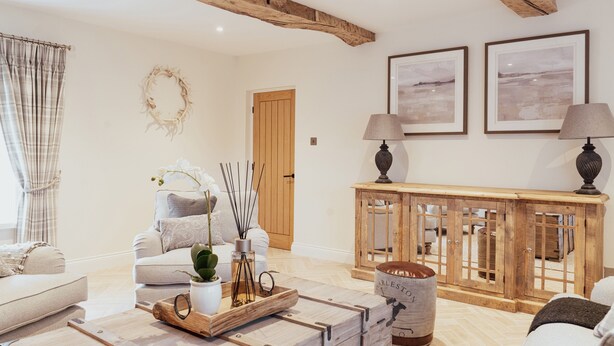 Una sala de estar acogedora con techo de madera, un sofá, una mesita de centro y una mesita auxiliar con lámpara.