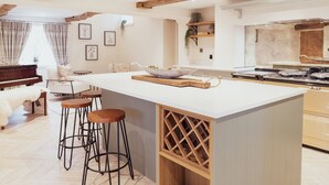 Una cocina moderna con una isla grande, taburetes de bar, un piano y un comedor con sofá blanco y sillas.