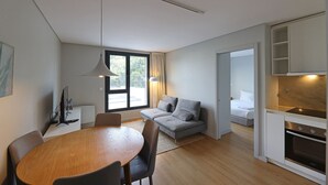 A modern, compact living space with a dining area, a sofa, a bed, and a kitchenette. - FLH Boavista Flat I (Oporto)