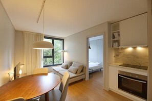 Une cuisine moderne dotée d’un four encastré et d’un coin repas avec une table et des chaises en bois.