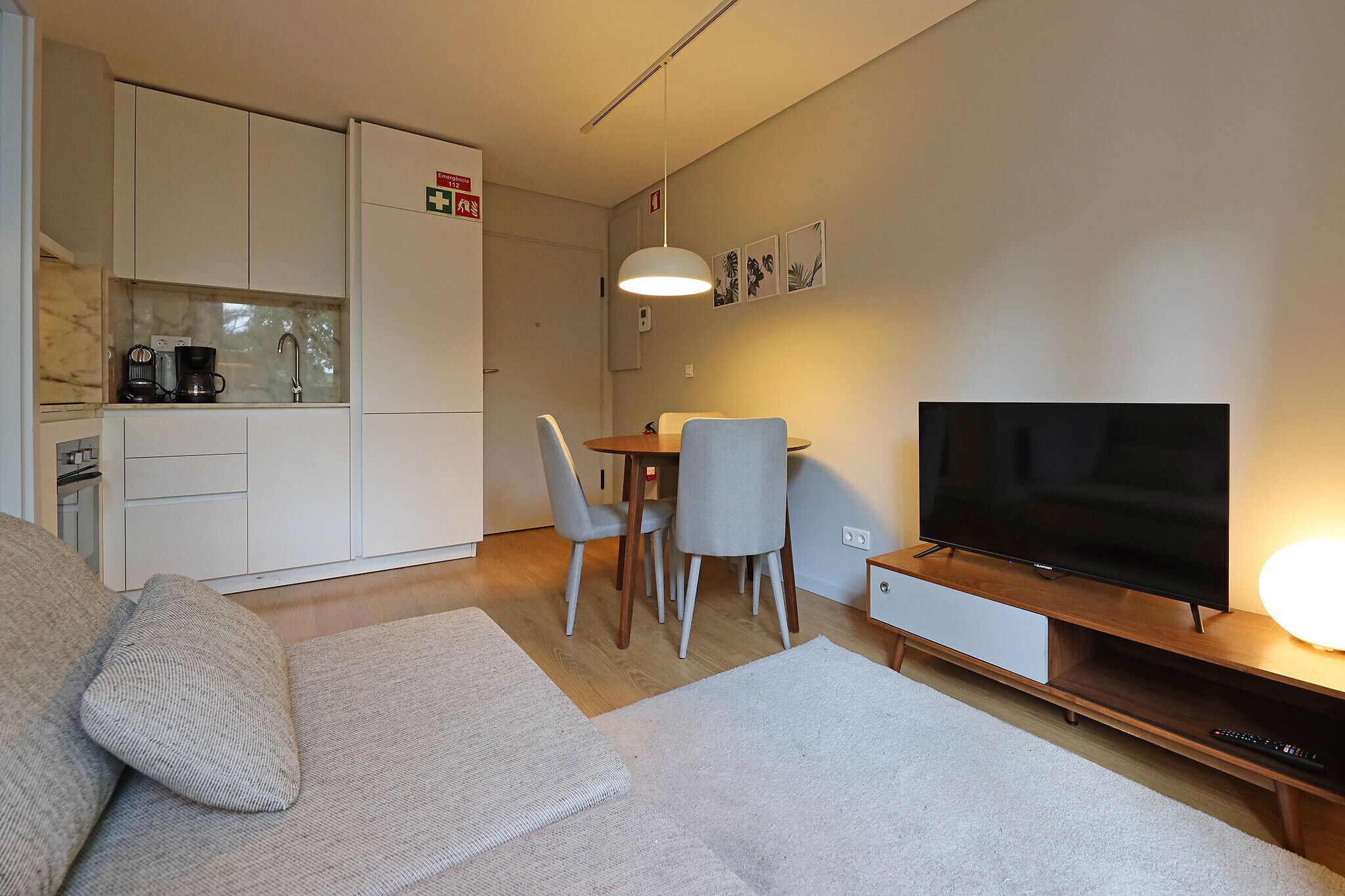 A compact living space with a kitchenette, dining area, and a TV.