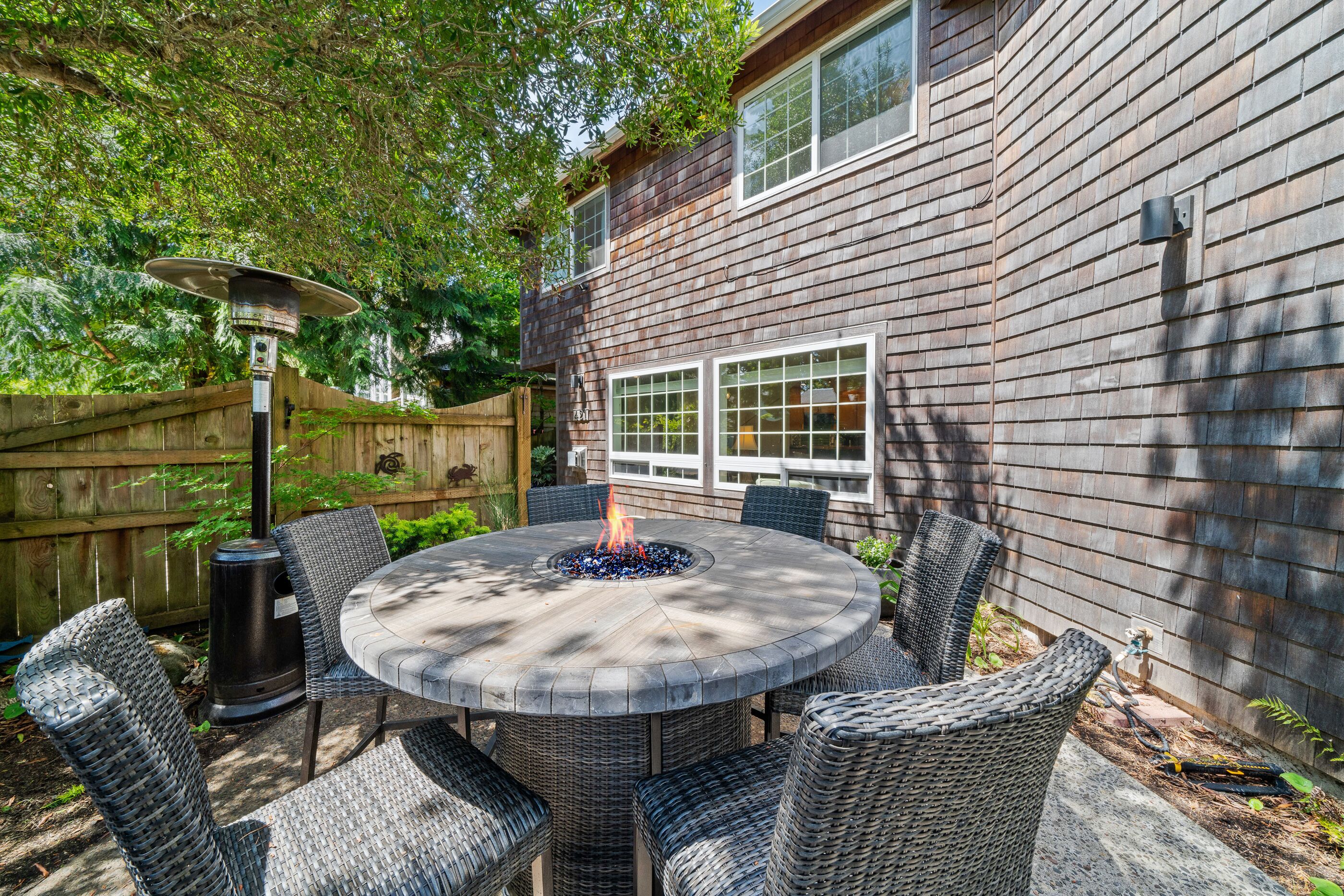 A round outdoor patio with a fire pit, wicker chairs, and a table.