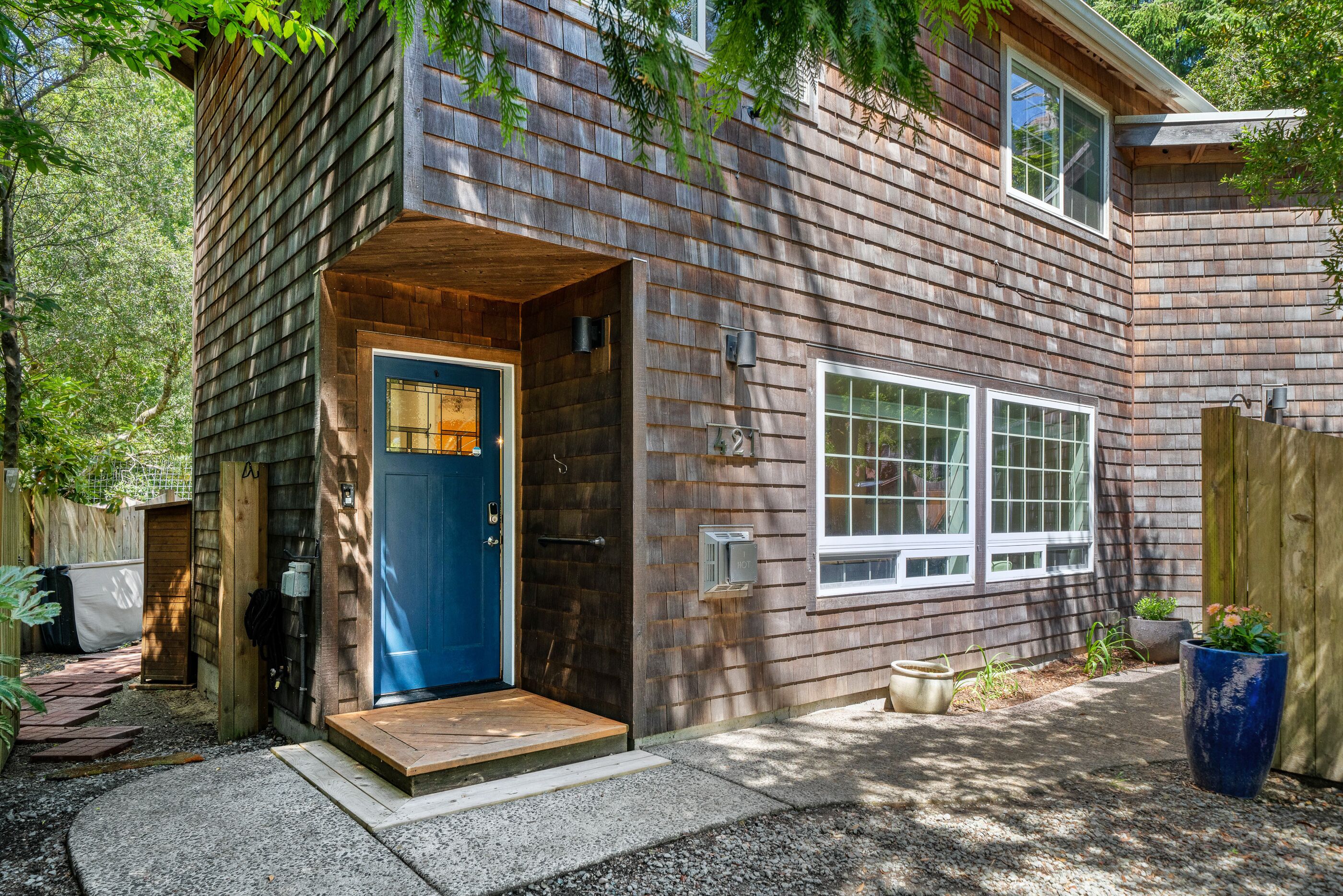 A wooden cabin with a blue door, a small porch, and a window.
