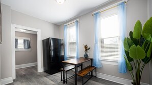 Una cocina con un refrigerador negro, una mesa de madera, un banco y una planta en maceta.