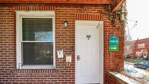 A brick building with a white door labeled "1682 A" and a window with blinds. There are two signs on the wall, one indicating "1682 B" and another with "1682 A" and "B".