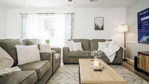 A modern living room with two grey sofas, a wooden coffee table, and a ceiling fan.