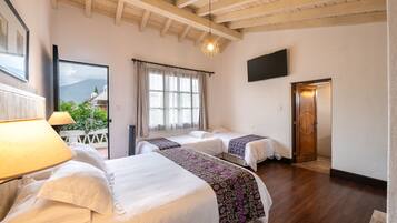 A hotel room with two beds, a TV mounted on the wall, and a wooden ceiling.