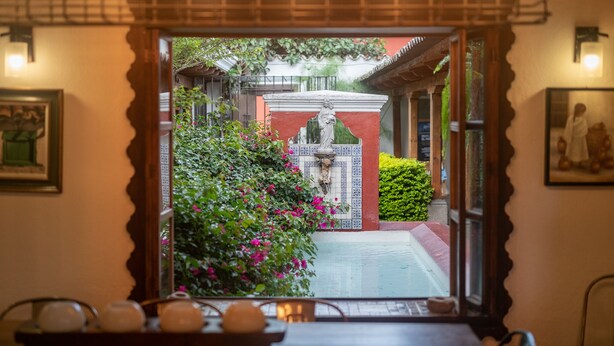 A traditional interior with a view of a garden through a doorway.