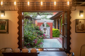 A traditional interior with a view of a garden through a doorway. - Barbaras Boutique Hostel (Antigua Guatemala)