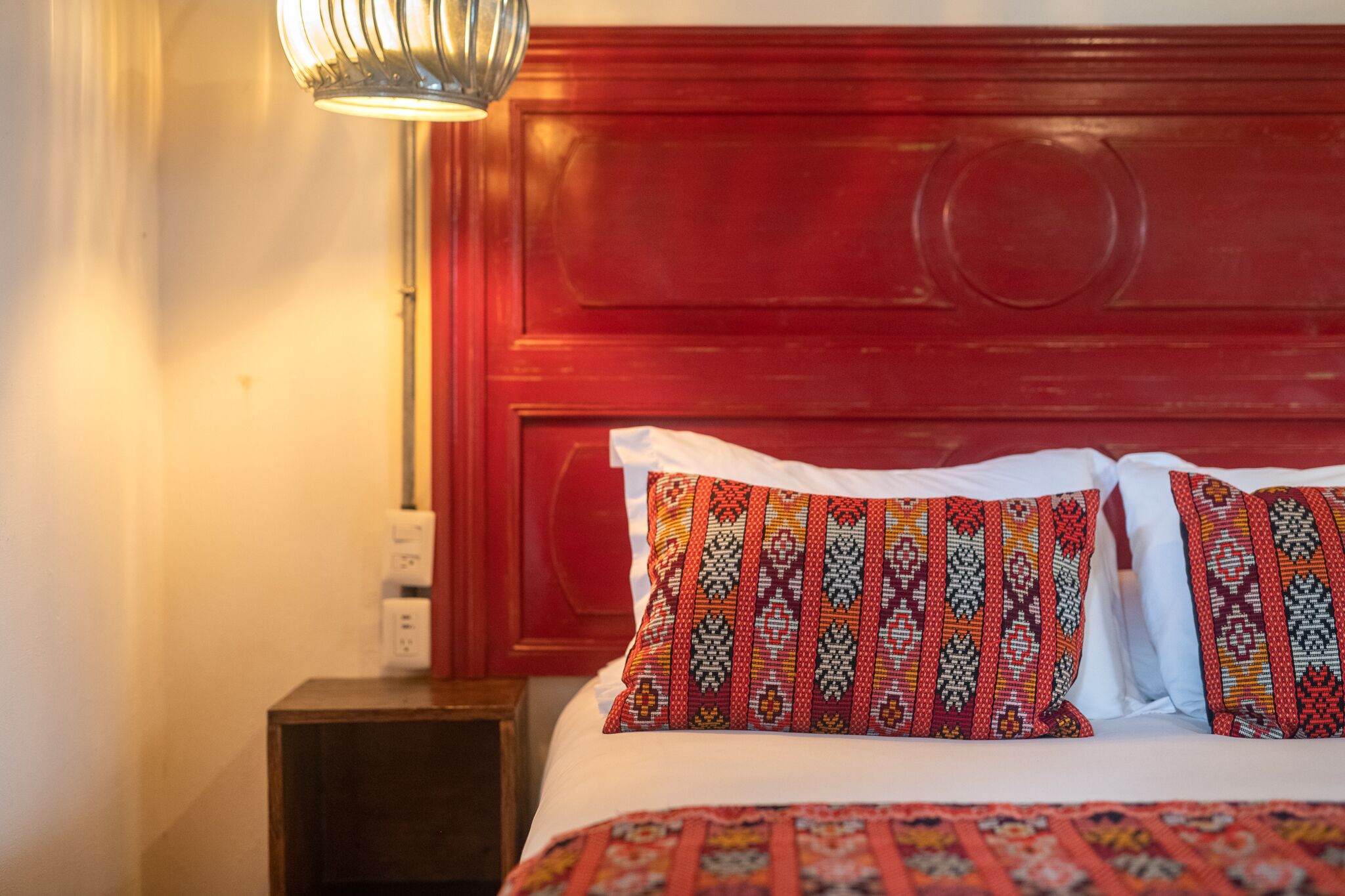 Una cama con almohadones estampados y cabecera de madera.