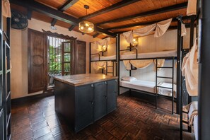 Una habitación rústica con literas, una encimera de madera y un ventilador.