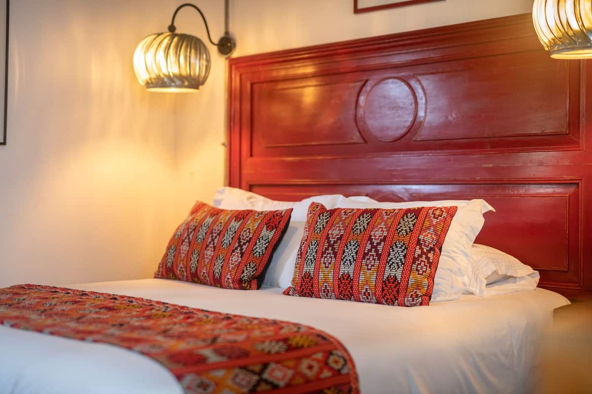 A neatly made bed with patterned pillows and a red headboard.