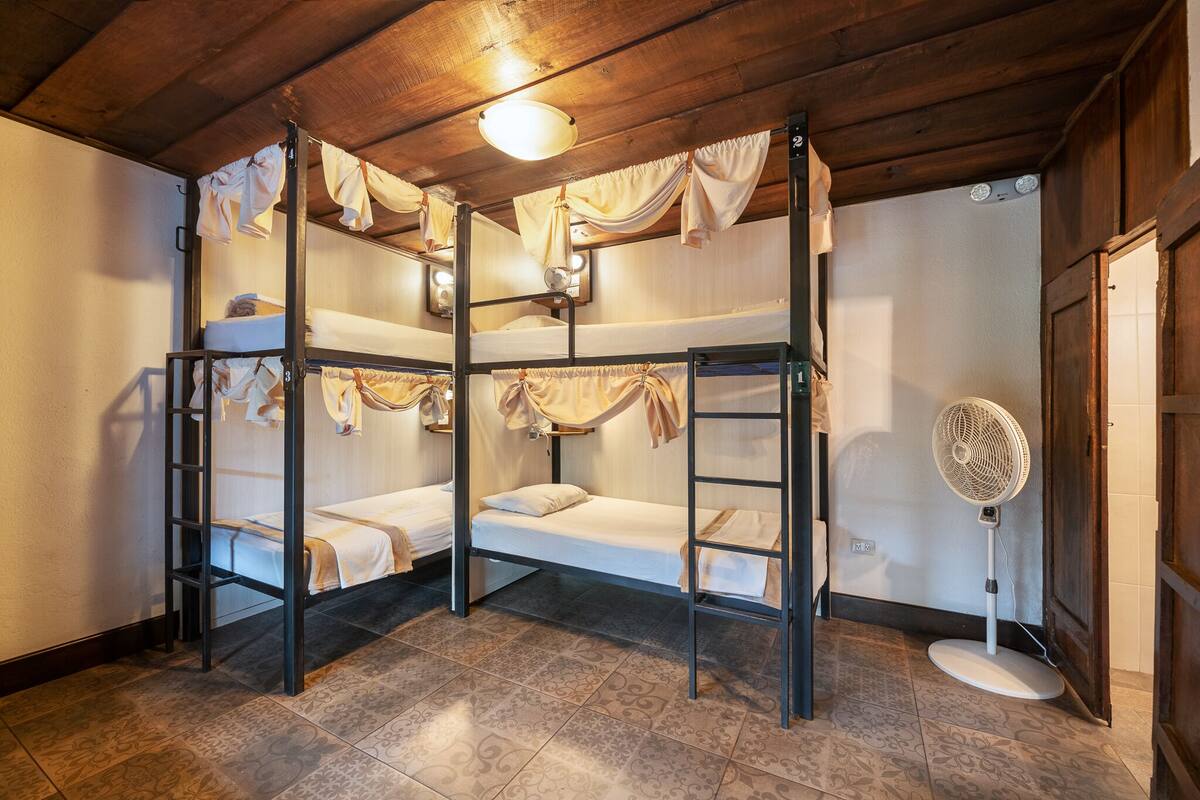 A bunk bed room with a fan and curtains.