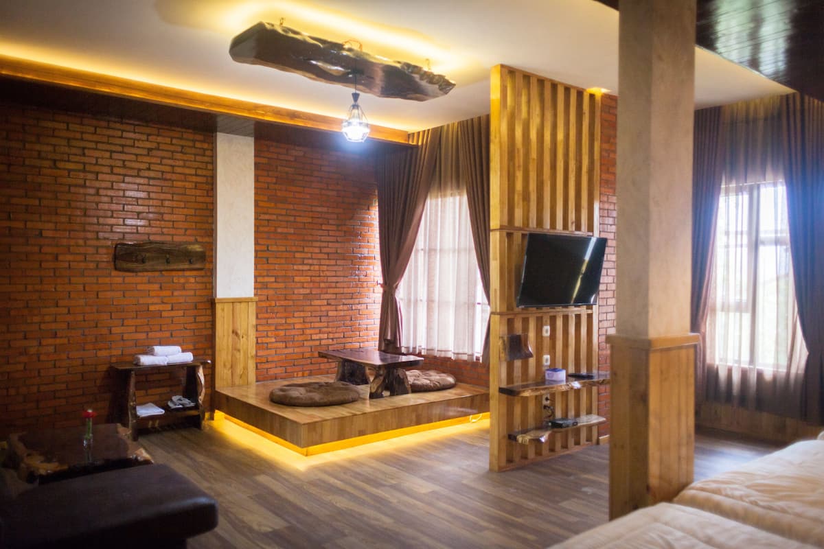 A modern room with a brick wall, wooden furniture, a flat-screen TV, and a cozy seating area.