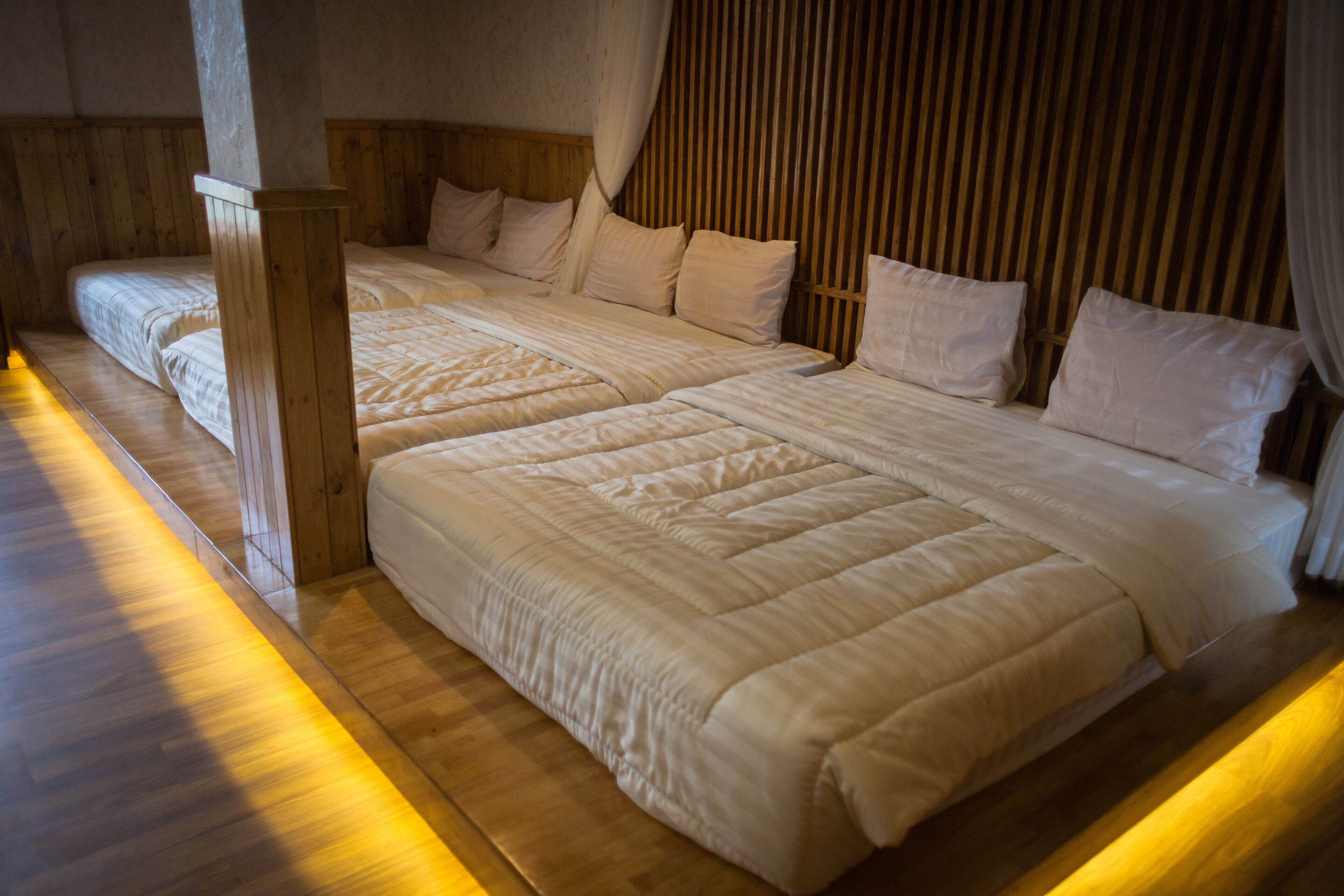 Habitación de hotel con dos camas, cabeceros de madera y suelo de madera.