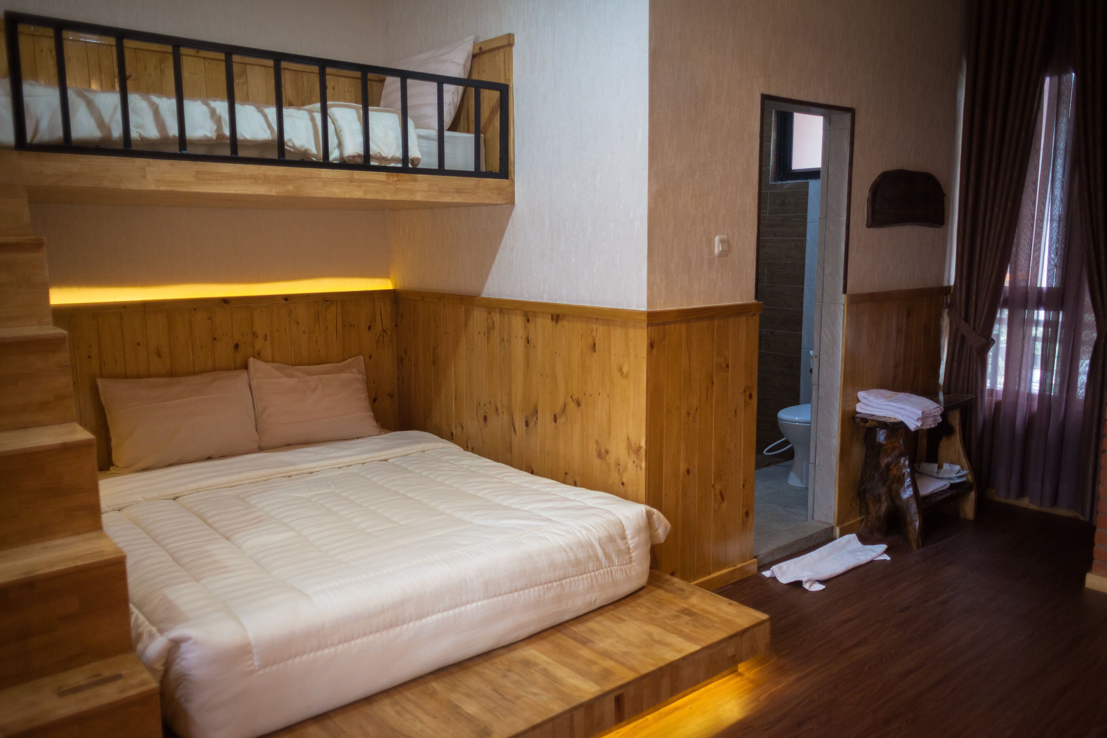 Ein Zimmer mit Etagenbett, Holzwänden, einem kleinen Badezimmer und einer Holztreppe.