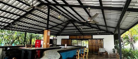 Un espace extérieur abrité, doté d’un comptoir incurvé, de sièges et d’une structure de toit en métal.