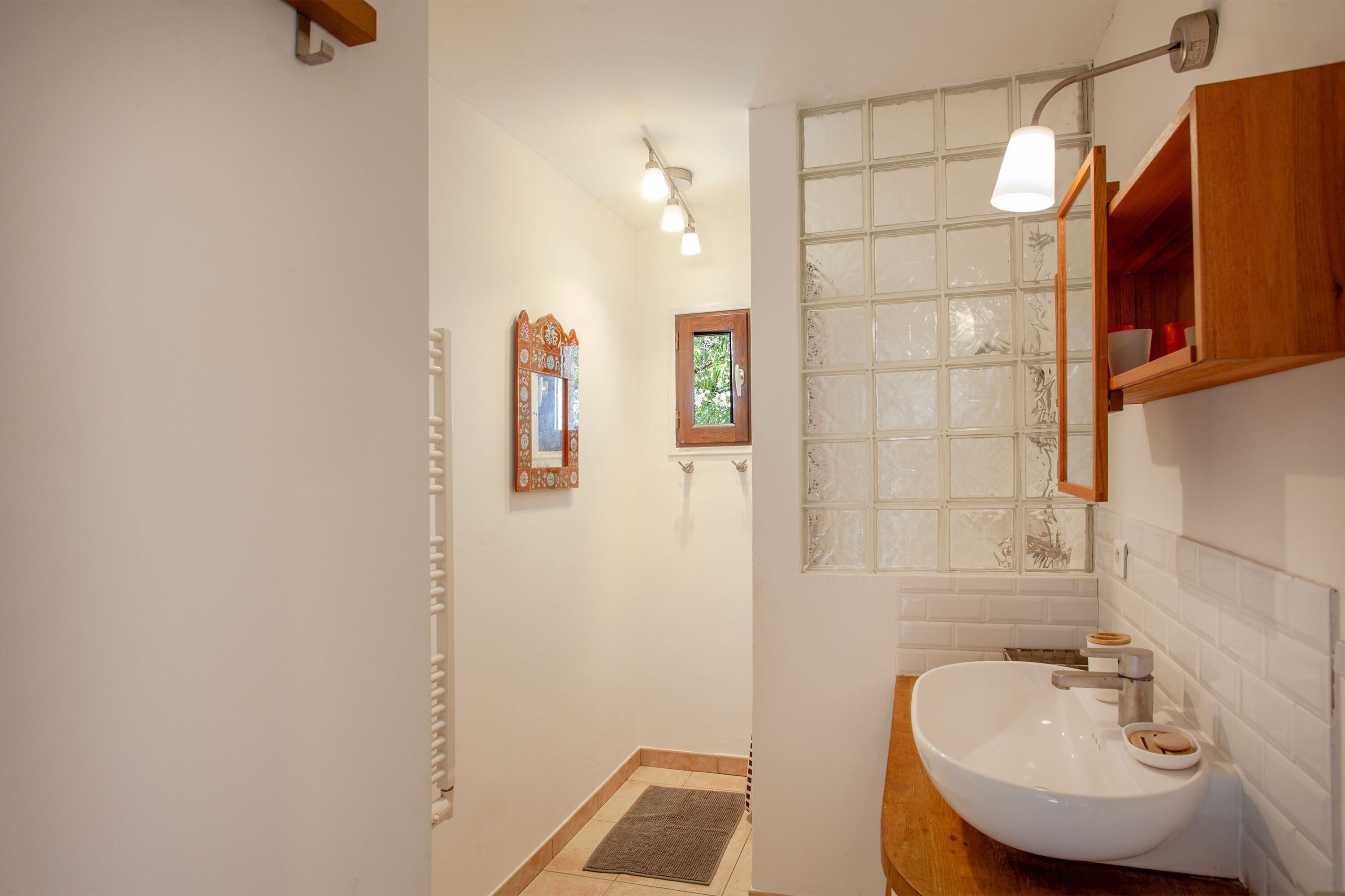 Une salle de bain avec un lavabo blanc, un meuble-lavabo en bois et une cabine de douche en verre.