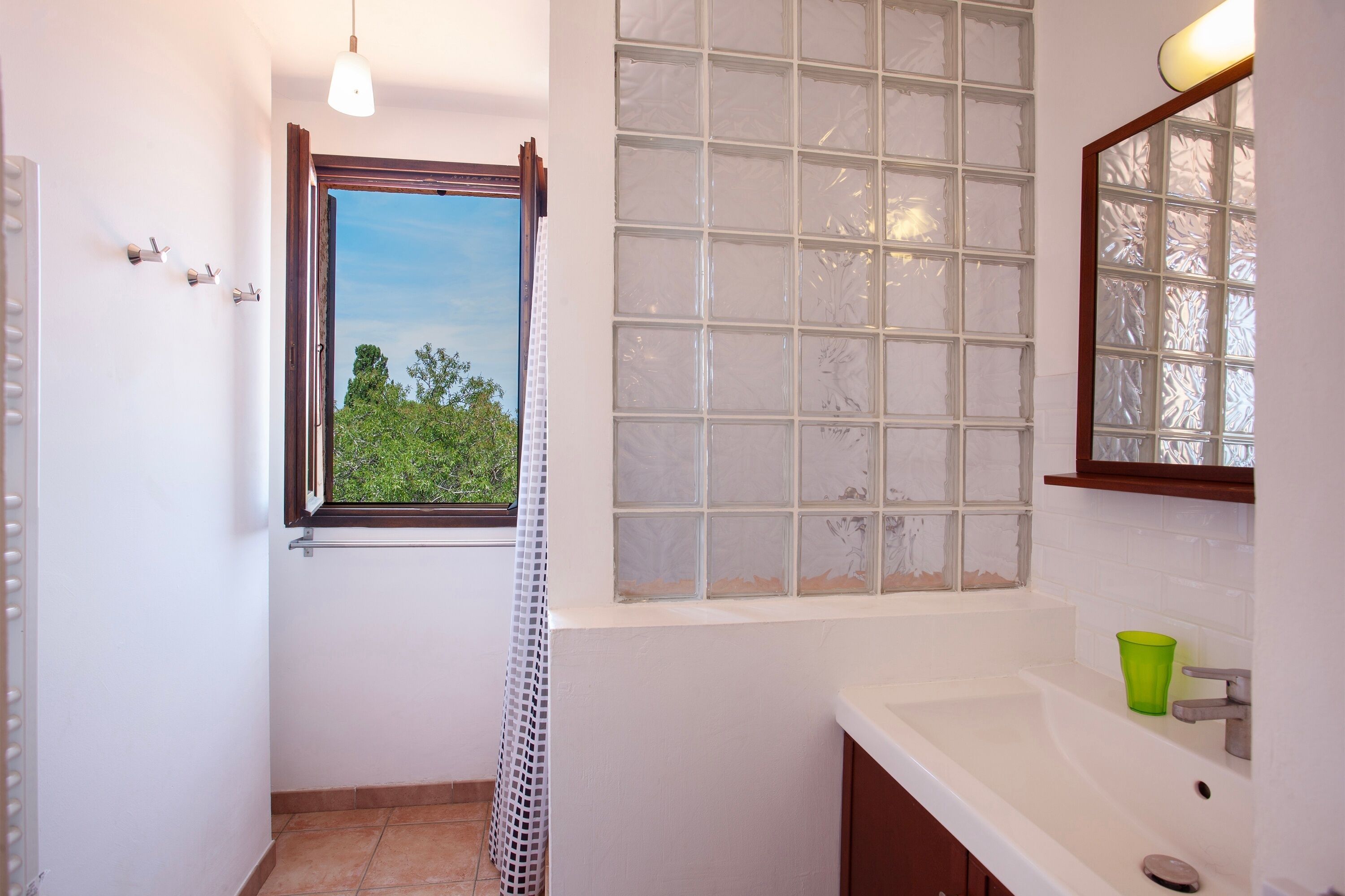 A bathroom with a window, a sink, and a mirror.