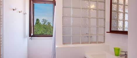 A bathroom with a window, a sink, and a mirror.