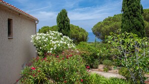 Un bâtiment doté d’un toit en tuiles, entouré d’une végétation luxuriante et de plantes en fleurs.