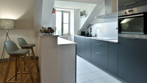 A modern kitchen with grey cabinets, a built-in oven, and a window providing natural light.