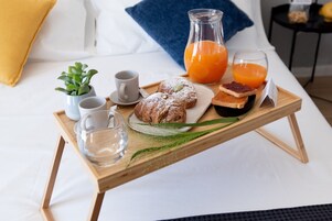 Ein Frühstückswagen mit Gebäck, Saft und Kaffee auf einem Bett.