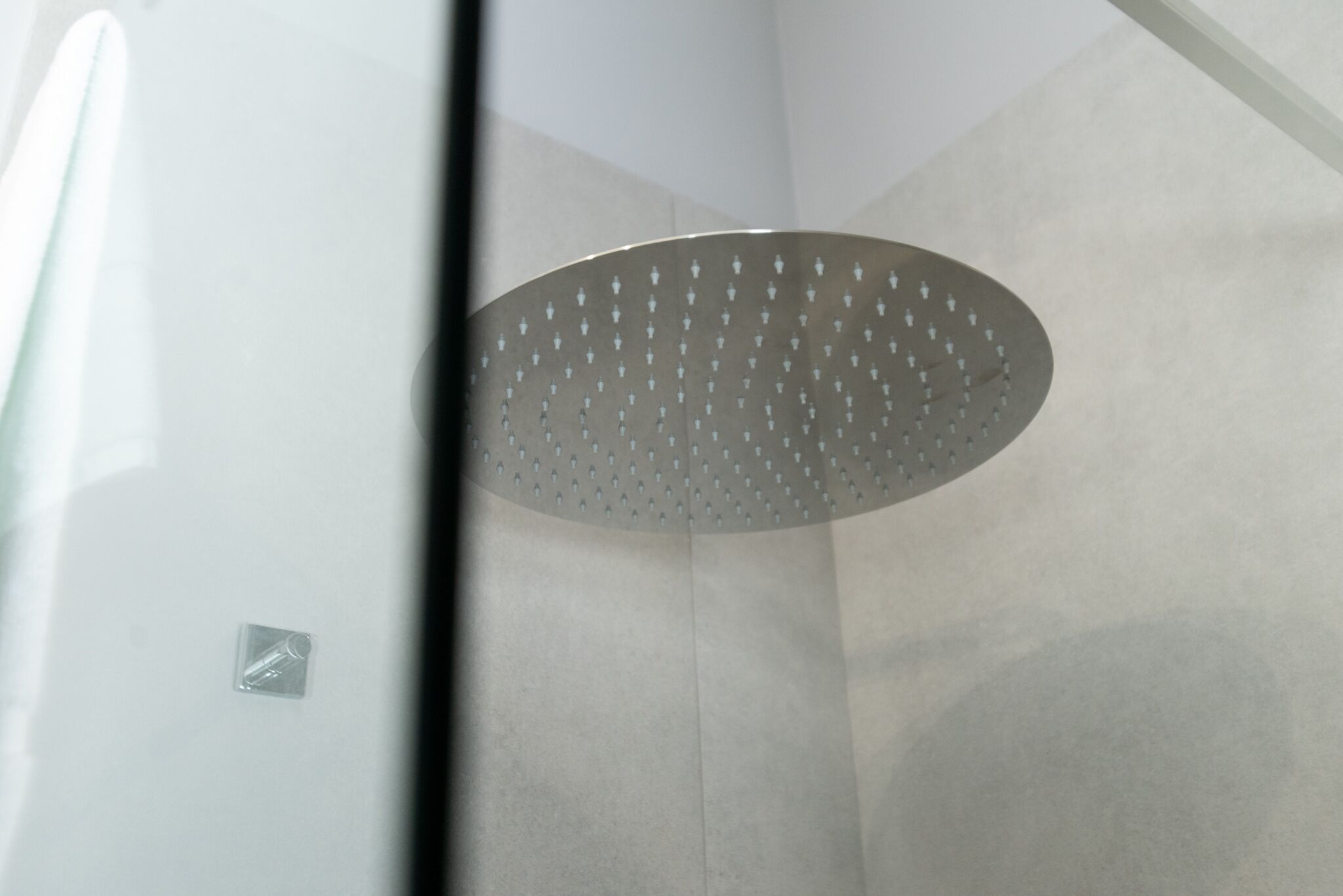 A modern shower with a circular, perforated ceiling.