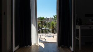 Een kamer met uitzicht op een balkon, een tafel met stoelen en een kleine plant in een pot.