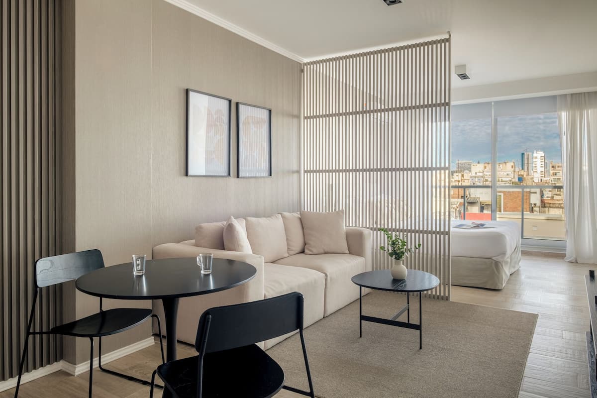 Una sala de estar moderna con un sofá, dos sillones, una mesita y un ventanal con vistas a la ciudad.