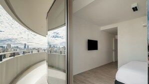 A modern hotel room with a balcony, a bed, a flat-screen TV, and a city view. - Nido x Recoleta Deco (Buenos Aires)