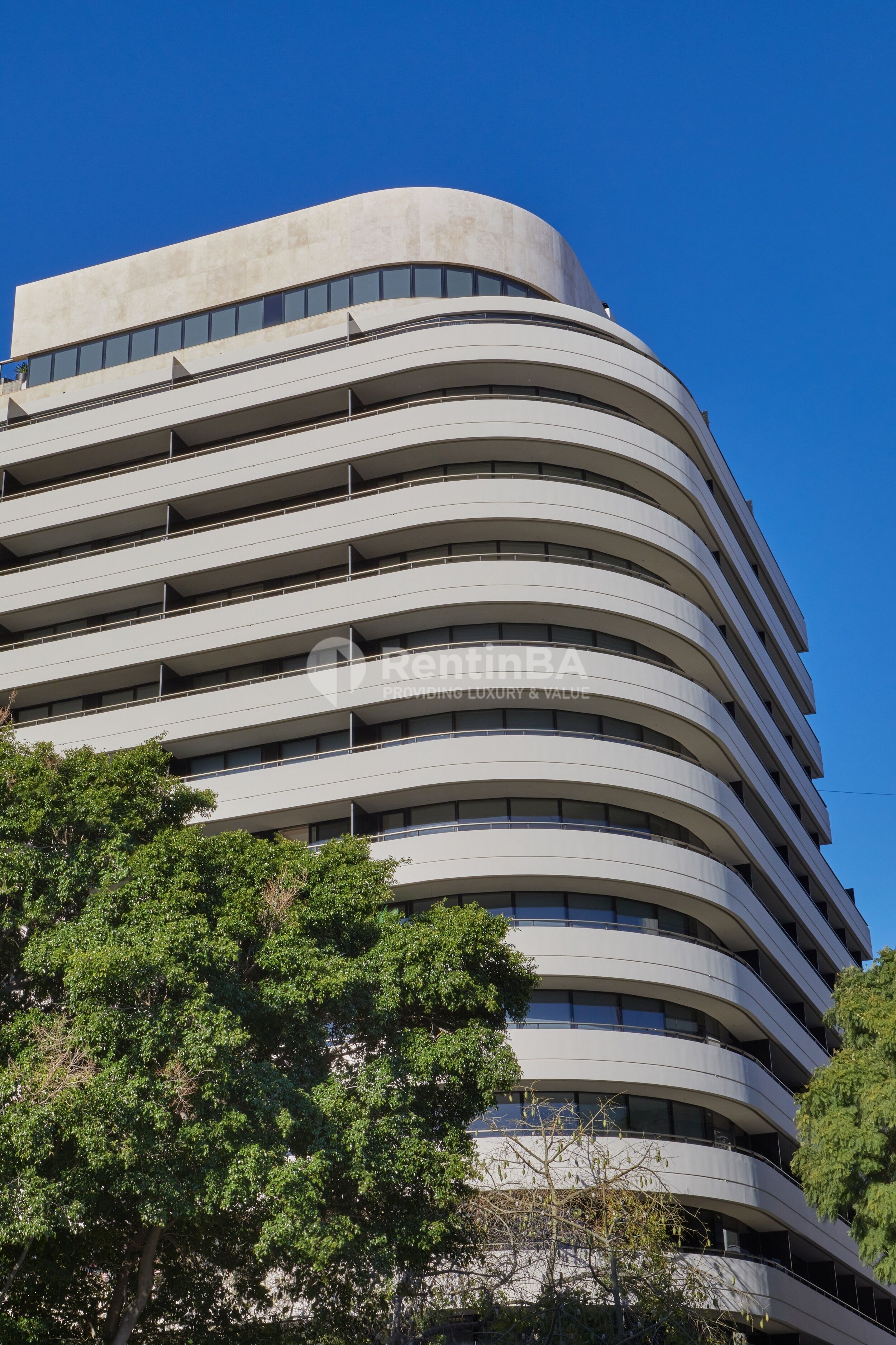 A modern multi-story building with a curved facade and numerous windows.