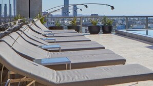 A rooftop terrace with sun loungers, potted plants, and a city skyline view. - Nido x Recoleta Deco (Buenos Aires)