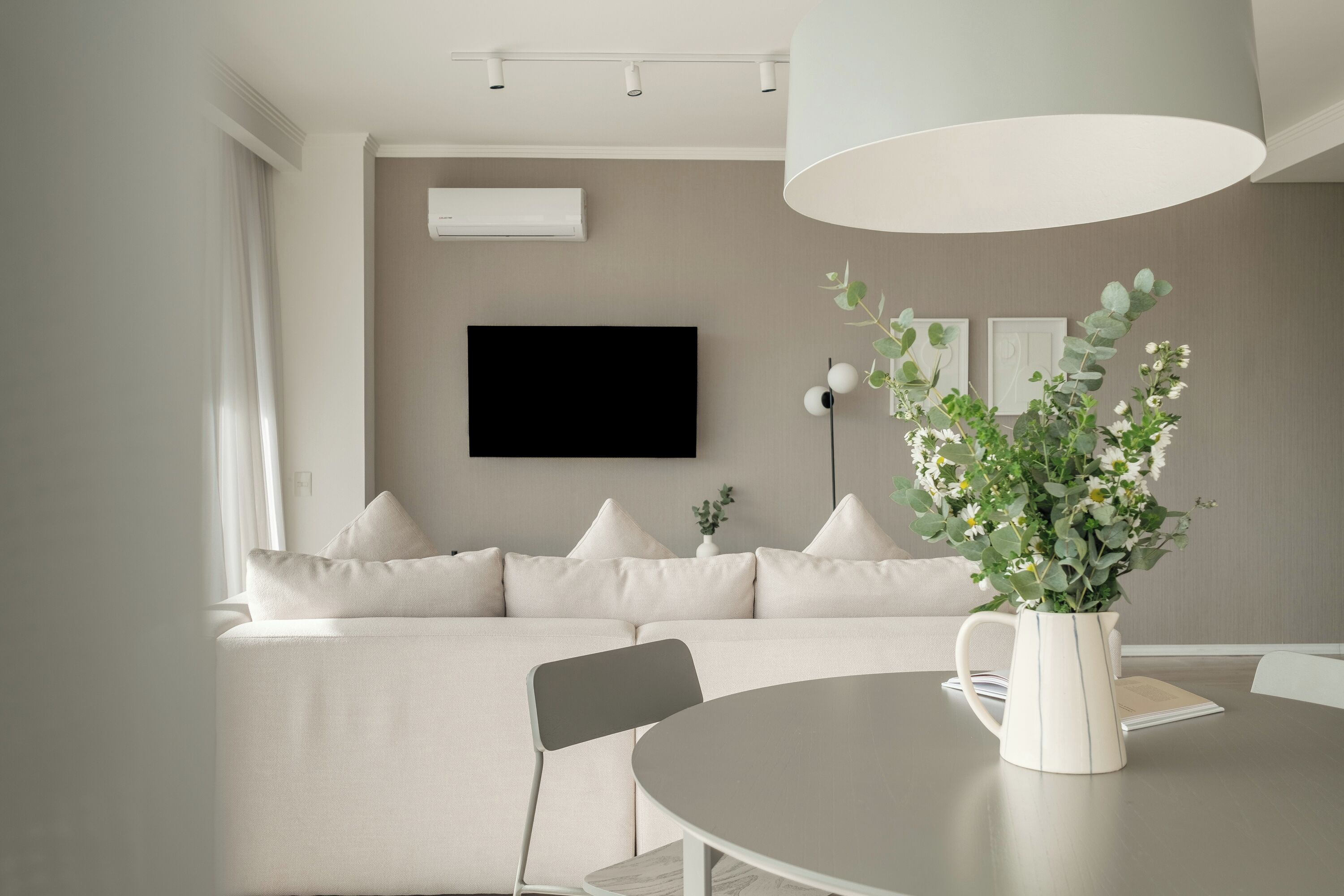 Una sala moderna con un sofá, una mesa de comedor y un televisor montado en la pared.