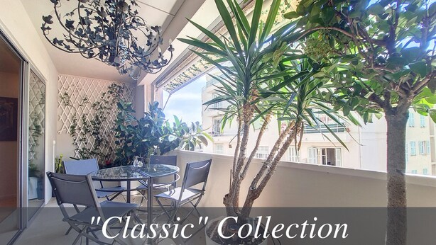 A balcony with a glass table and chairs, surrounded by potted plants and a decorative metal chandelier. - N&J - FLEURS TERRASSE - 3 bedrooms (Niza)
