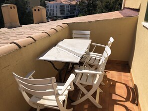 Ein Balkon mit Fliesenboden, einem weißen Tisch und weißen Stühlen.