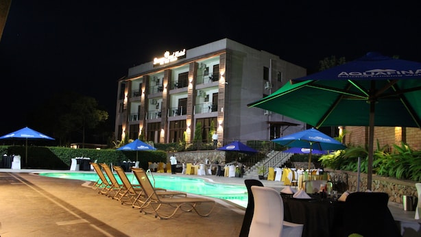 A hotel with a swimming pool, outdoor seating, and umbrellas.