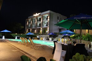 Hotel com piscina, área de estar externa e guarda-sóis.