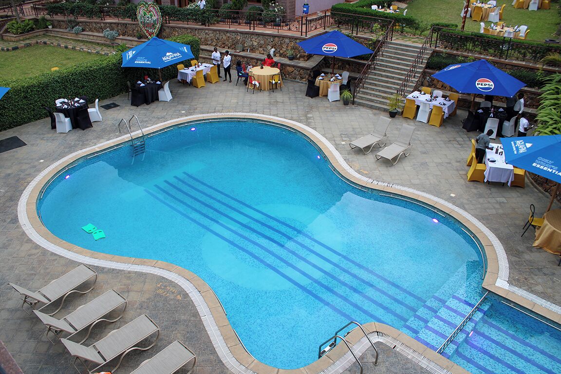 A swimming pool with lounge chairs and tables, surrounded by umbrellas and outdoor seating.