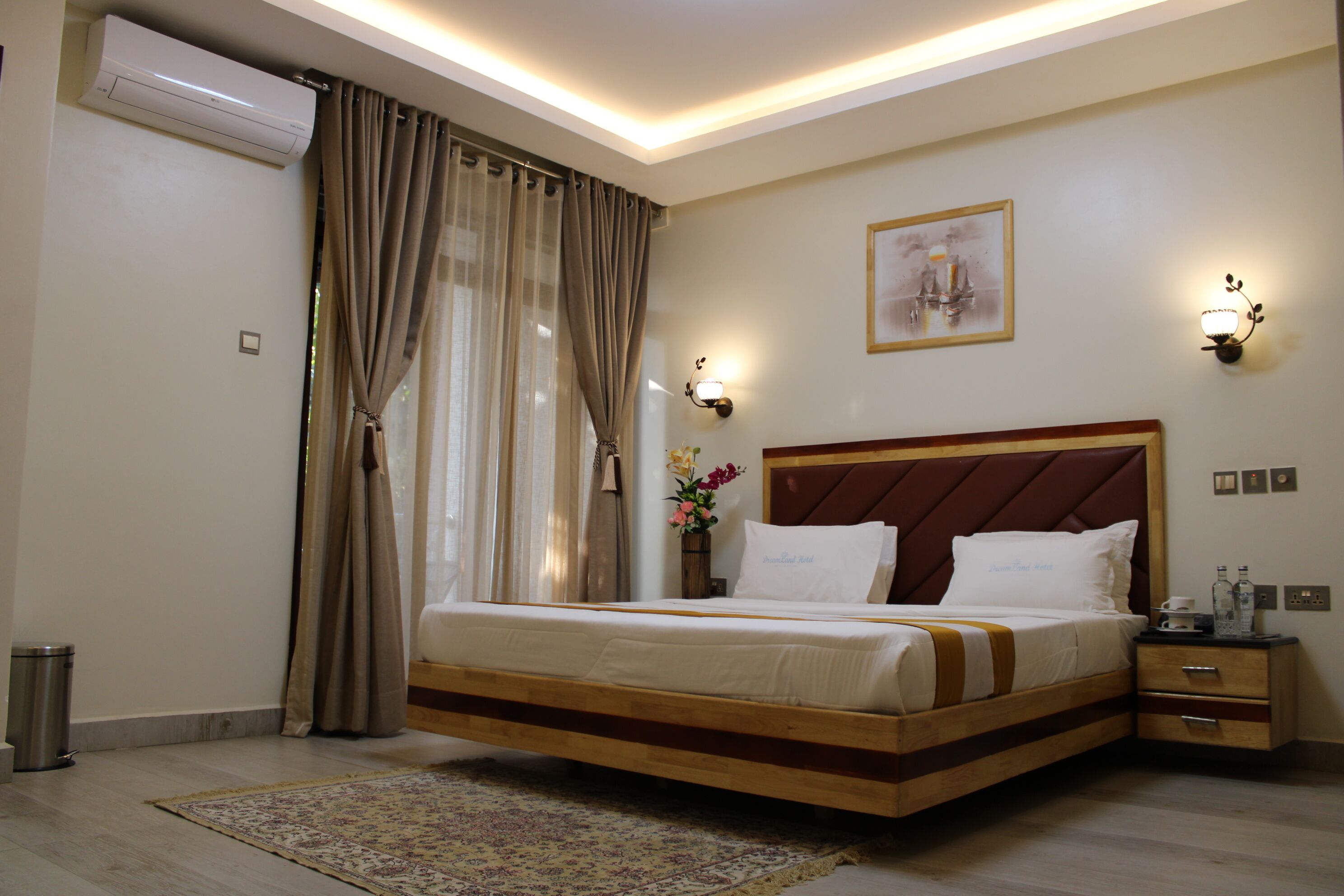 Habitación de hotel con una cama grande, una mesita de noche, una lámpara de pared e imagen en la pared.