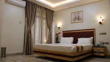 Habitación de hotel con una cama grande, una mesita de noche, una lámpara de pared e imagen en la pared.